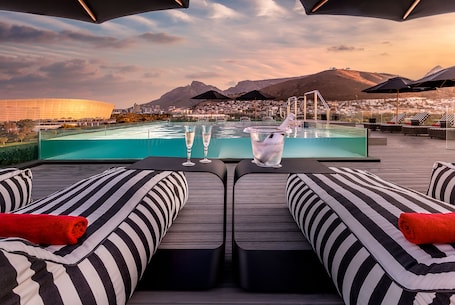 Una piscina al aire libre, sombrillas, sillones reclinables de piscina