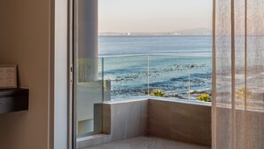 A balcony with a view of the sea, a chair with a yellow blanket, and a modern interior design.