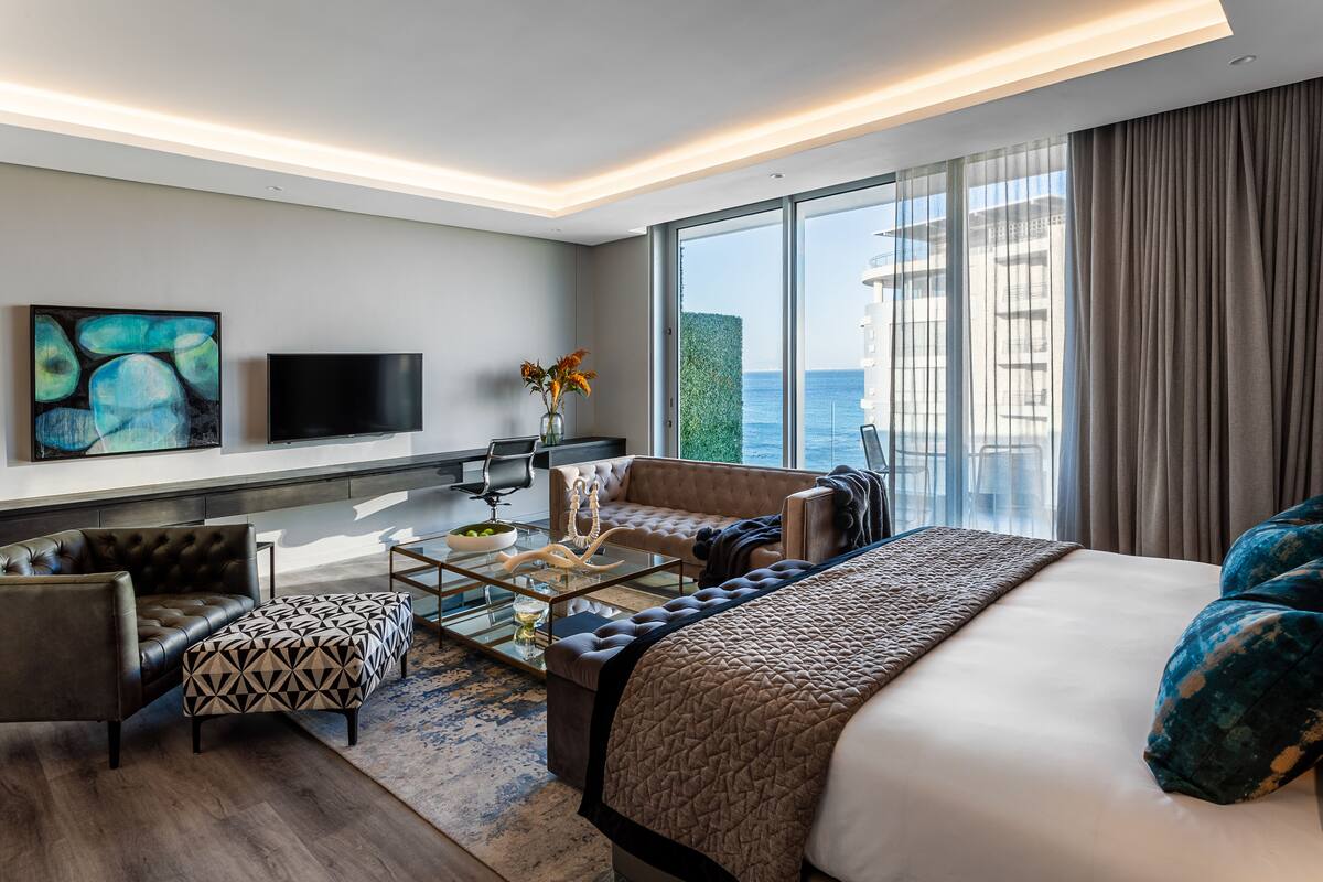 Une chambre d’hôtel moderne avec un grand lit, un canapé, une table basse et un téléviseur.