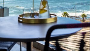 A table with a glass and a tray, overlooking a beach with the ocean and a distant island.