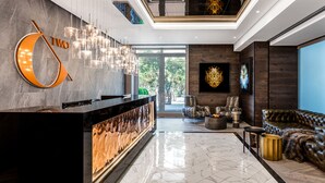 A modern lobby with a reception desk, a chandelier, a sofa, and a large window.