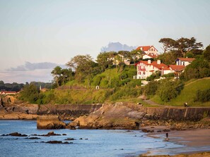 Une ville côtière avec des maisons construites sur une colline, un mur de pierre et une plage.