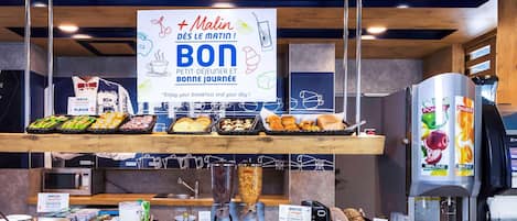 A breakfast buffet with various food items, a coffee machine, and a sign promoting a morning meal.