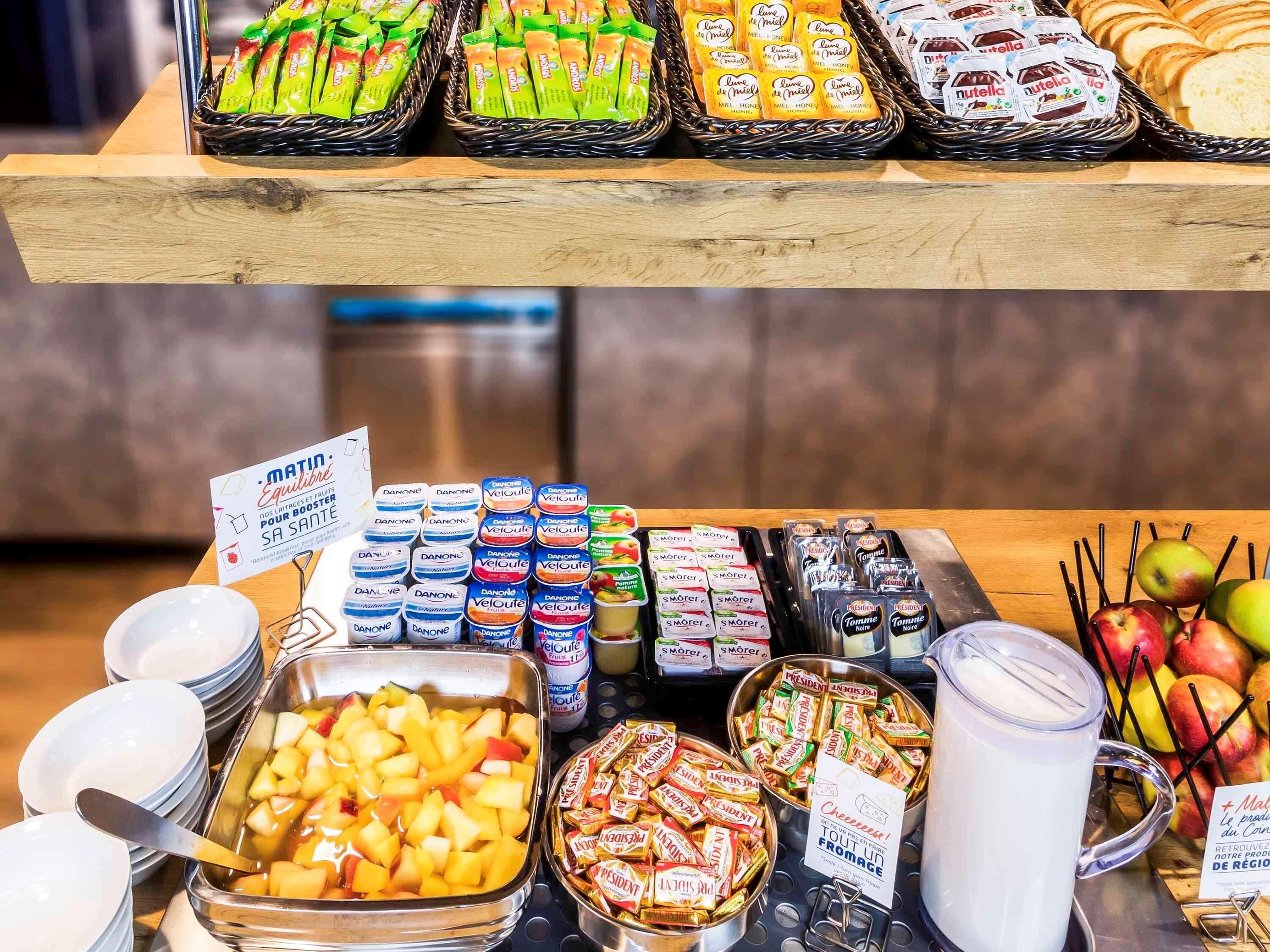 Een buffet met diverse etenswaren, zoals fruit, kazen en verpakte snacks.