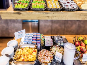 A buffet with various food items including fruits, cheeses, and packaged snacks. - Ibis Budget Biarritz Anglet (Anglet)