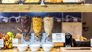A breakfast buffet with cereal options, fruits, and bread. - Ibis Budget Biarritz Anglet (Anglet)