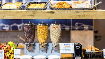 Un bufé de desayuno con opciones de cereales, frutas y pan.