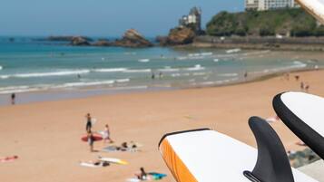 Una playa con tablas de surf, una orilla arenosa y edificios a la distancia.