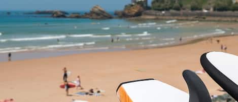 A beach with surfboards, a sandy shore, and distant buildings.