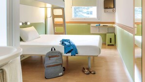 A compact, well-lit room with a bunk bed, a small desk, and a TV.