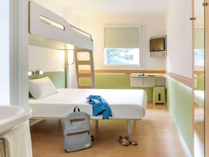 A compact, well-lit room with a bunk bed, a small desk, and a TV.