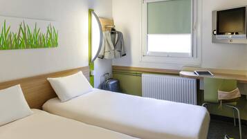 Habitación de hotel con dos camas, un escritorio con computadora, una ventana y un radiador.