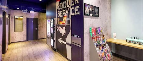 Un área de recepción con un letrero que indica 'Cooler Service', una exhibición de revistas y un mostrador con un menú.