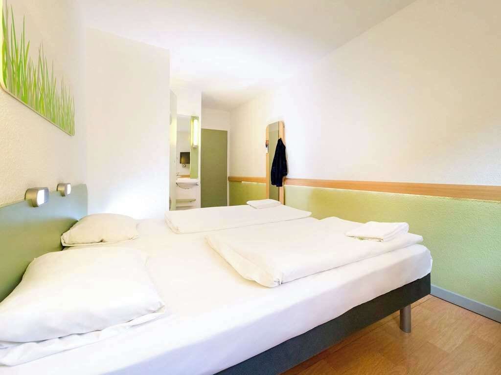 A hotel room with a bed, a mirror, and a green wall.