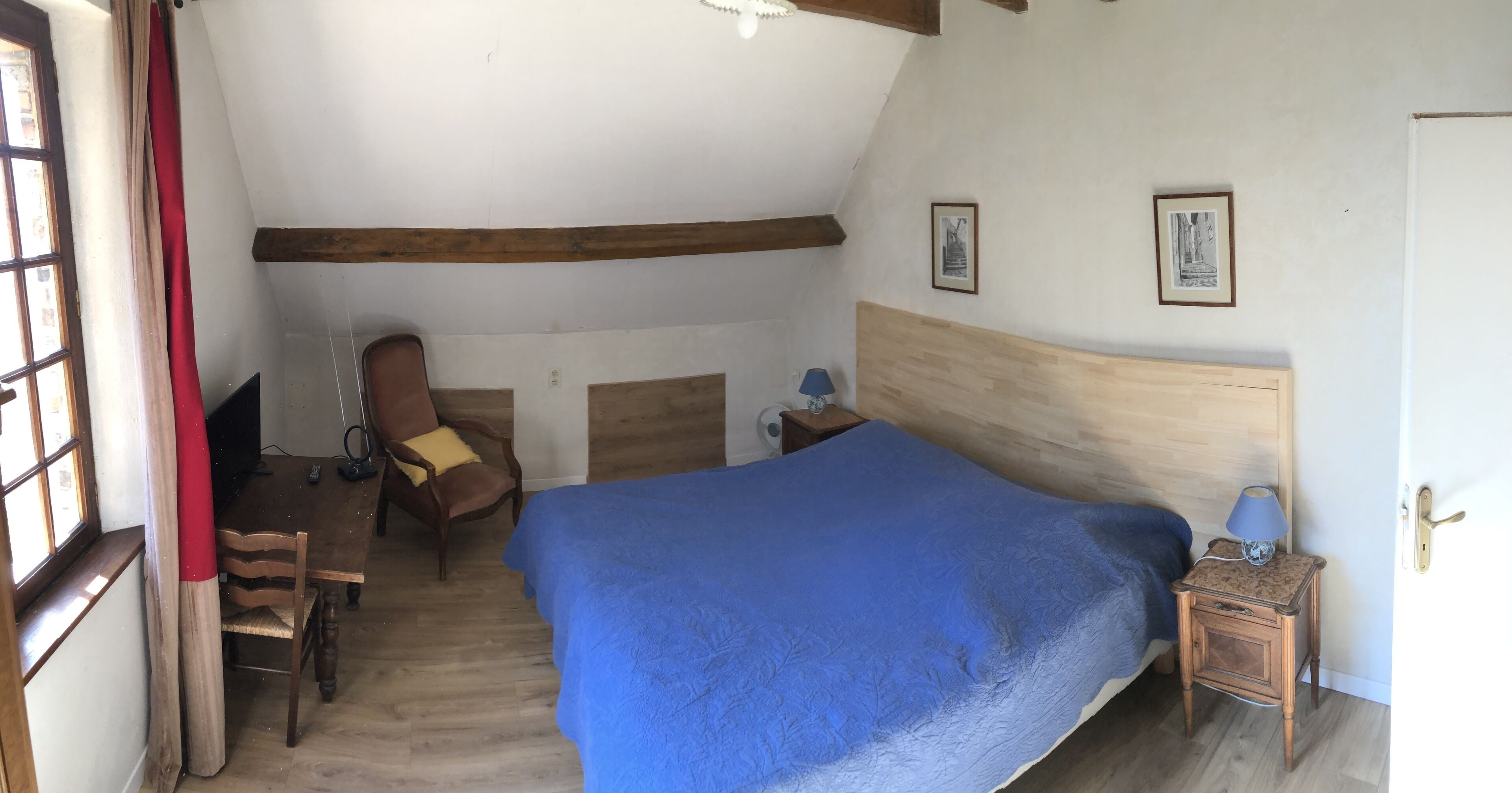 A bedroom with a large bed, wooden headboard, a chair, a nightstand, and a door.