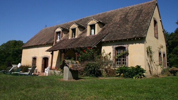 A two-story building with a sloped roof, a stone foundation, and a small porch with a stone bench. - La Jonquière (Bouloire)