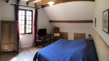 Un dormitorio con cama, armario de madera, escritorio, silla y ventana con cortinas.