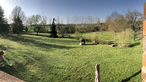 A grassy outdoor area with trees and a brick wall. - La Jonquière (Bouloire)