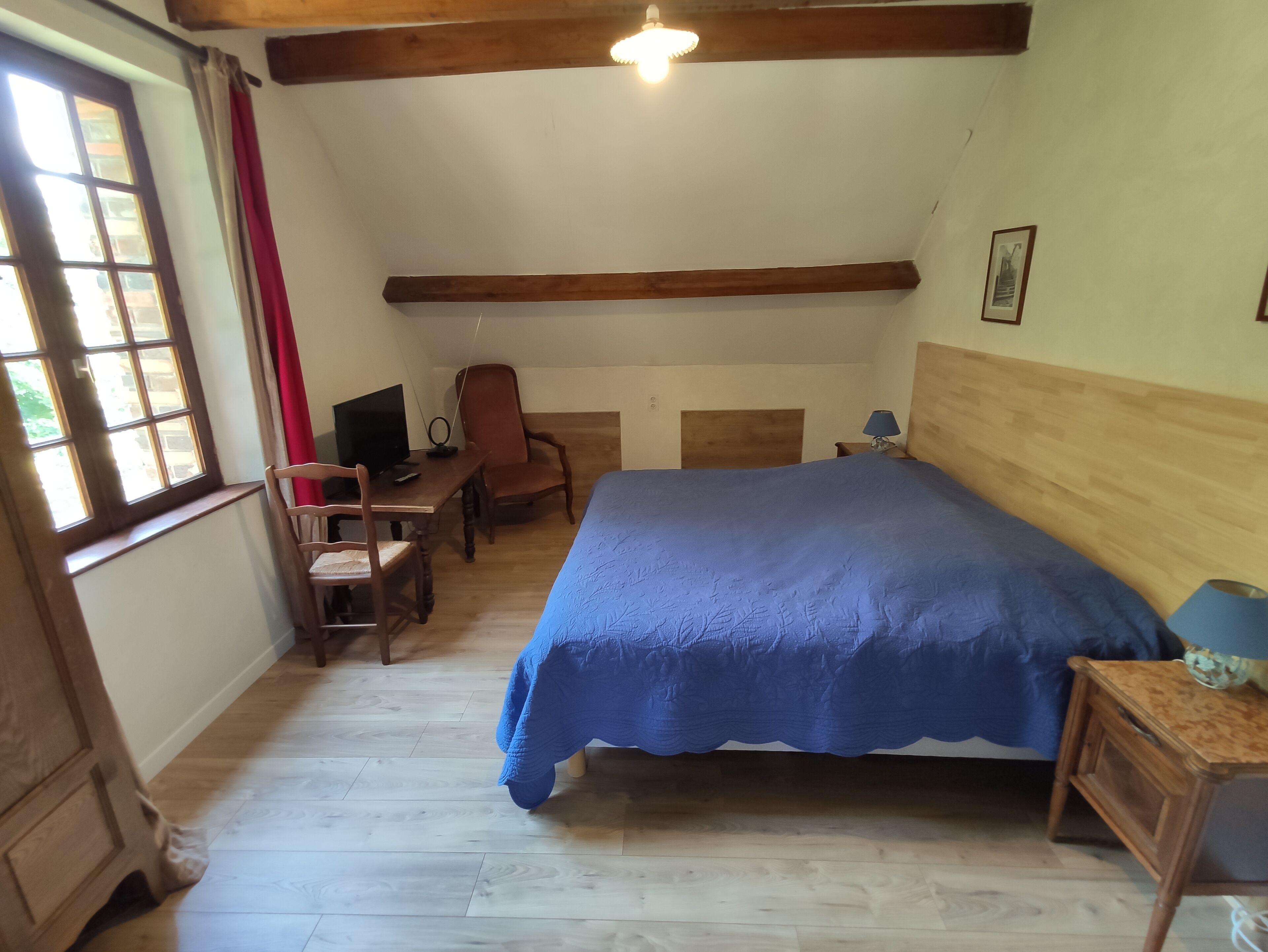 Une chambre à coucher comprenant un lit, un bureau, une chaise, une fenêtre et un luminaire au plafond.