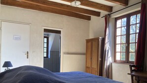 A bedroom with a bed, a wooden wardrobe, a radiator, a door, and a window with curtains. - La Jonquière (Bouloire)