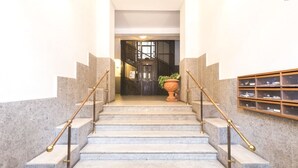 A marble staircase with brass railings leading to a dark wooden door.