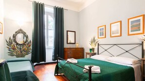 A bedroom with two beds, a wooden dresser, a mirror, and framed pictures on the wall.