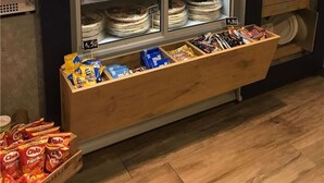 Ein gekühlter Warenkorb mit Getränken und Snacks, eine Mikrowelle und eine Küchenecke-Beschilderung.