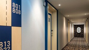 Ein Flur mit nummerierten Türen, einem gemusterten Boden und einer Wand mit Nummern.