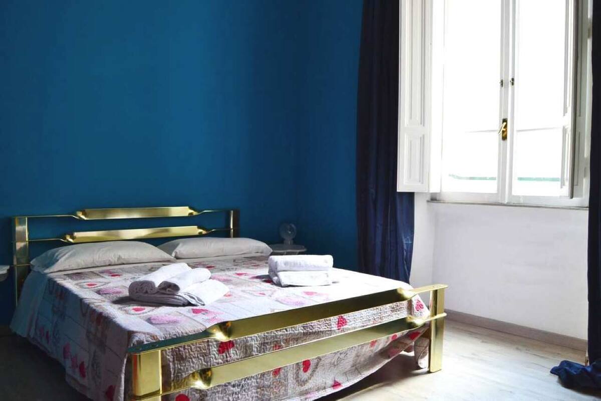 A bedroom with a bed, a nightstand, and a window with curtains.