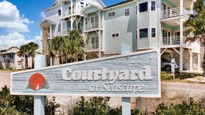 Bordje voor 'Courtyard at Seascape' met een kustthema, inclusief een palmboom en een strandscène.