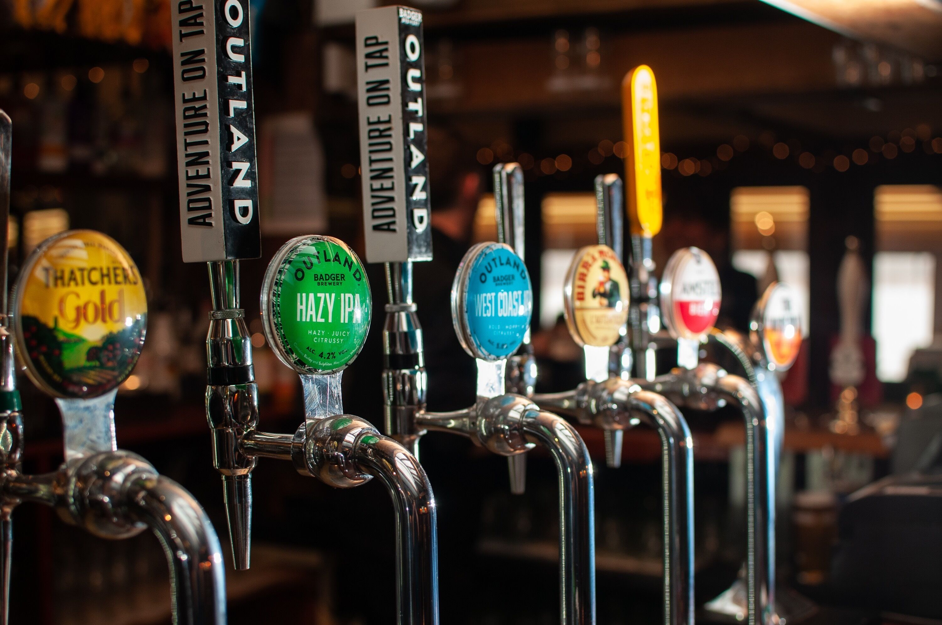 A row of beer taps with labels indicating different beer brands and types.