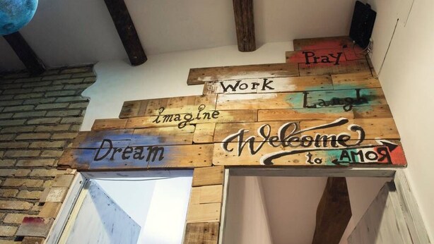 Ein hölzernes Schild mit motivierenden Sprüchen wie "Imagine", "Dream", "Welcome" und "Work".