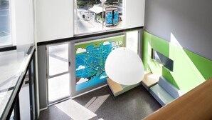 Un interior moderno con un mural de un mapa, una zona de bar y una escalera.
