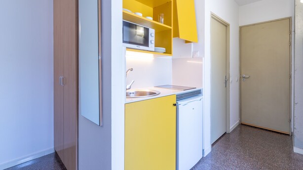 Cocina compacta con gabinetes amarillos, un microondas y un lavabo.