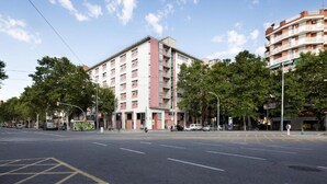 Un edificio de varios pisos con un diseño arquitectónico moderno, que presenta una combinación de balcones y ventanas.