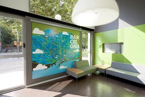 Ein modernes Interieur mit einer großen Karte von Barcelona, Sitzbereichen und einem großen Fenster.
