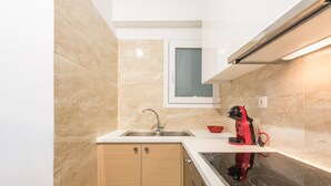 Una cocina moderna con horno empotrado, pileta de acero inoxidable y una cafetera roja.
