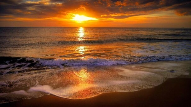 A beach scene with waves and a sunset.
