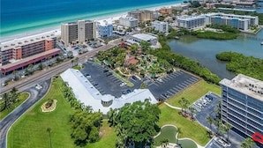 An aerial view of a coastal city with a marina, a parking lot, and buildings with varying heights.
