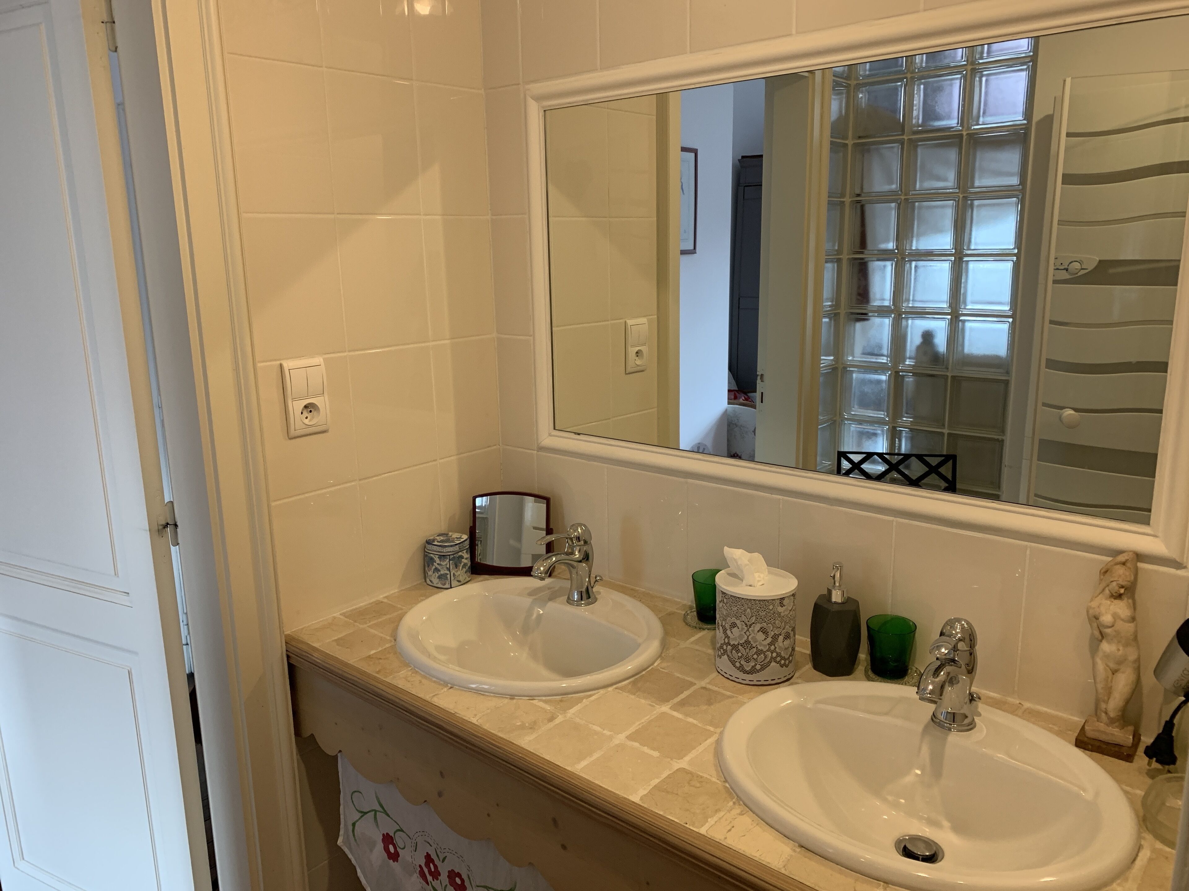 A bathroom with two sinks, a mirror, and a window with frosted glass.