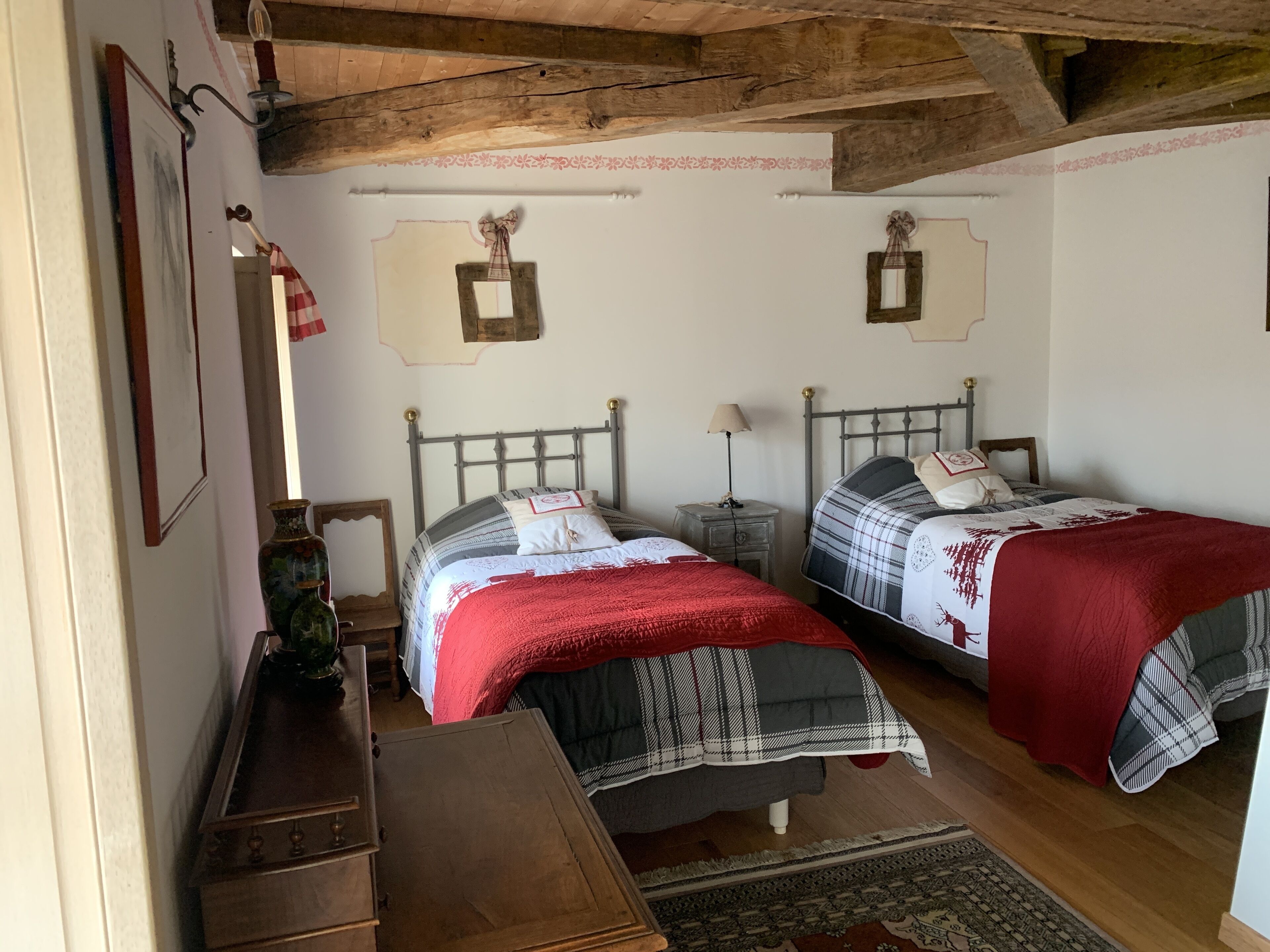 Un dormitorio con dos camas, cabeceros de madera, una mesita de noche con lámpara, un aparador y una alfombra.
