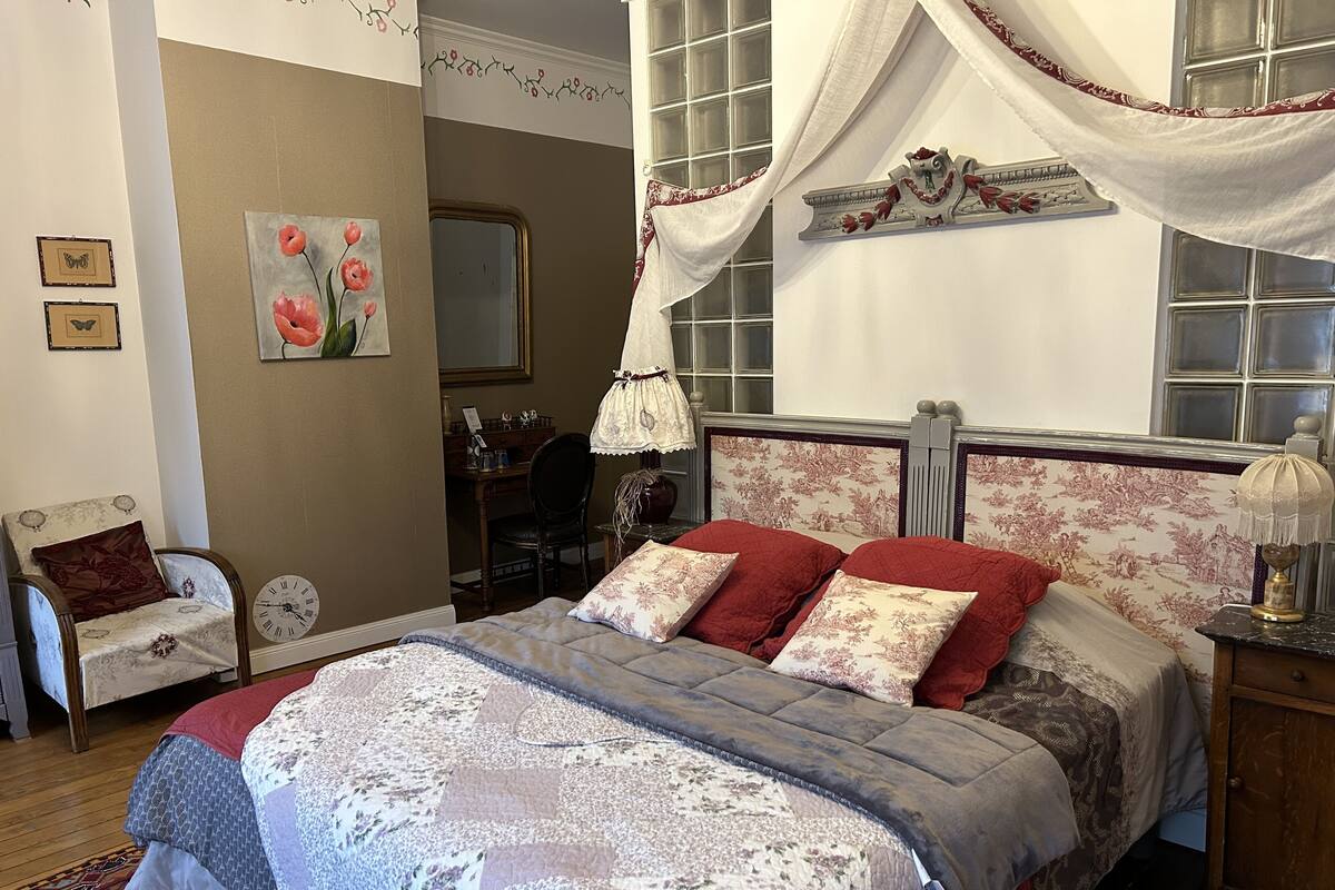 Un dormitorio con una cama, una silla, un escritorio y un espejo.