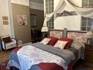Un dormitorio con una cama, una silla, un escritorio y un espejo.