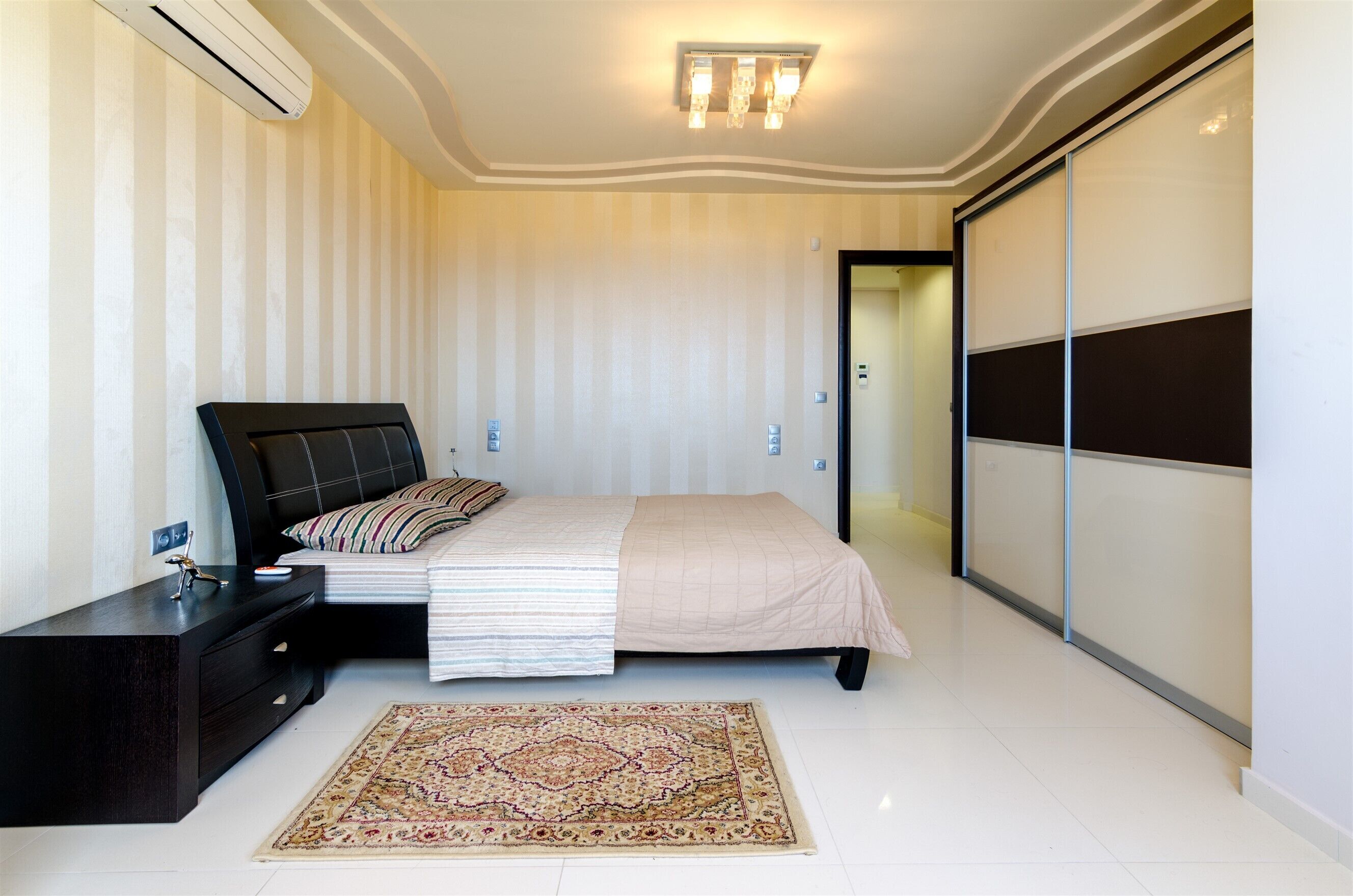 Een slaapkamer met een bed, nachtkastje en een groot vloerkleed.