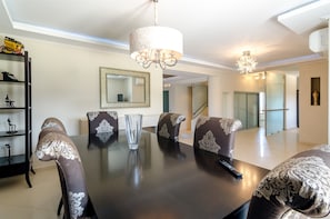 A dining area with a dark table, patterned chairs, a chandelier, and a large mirror on the wall.