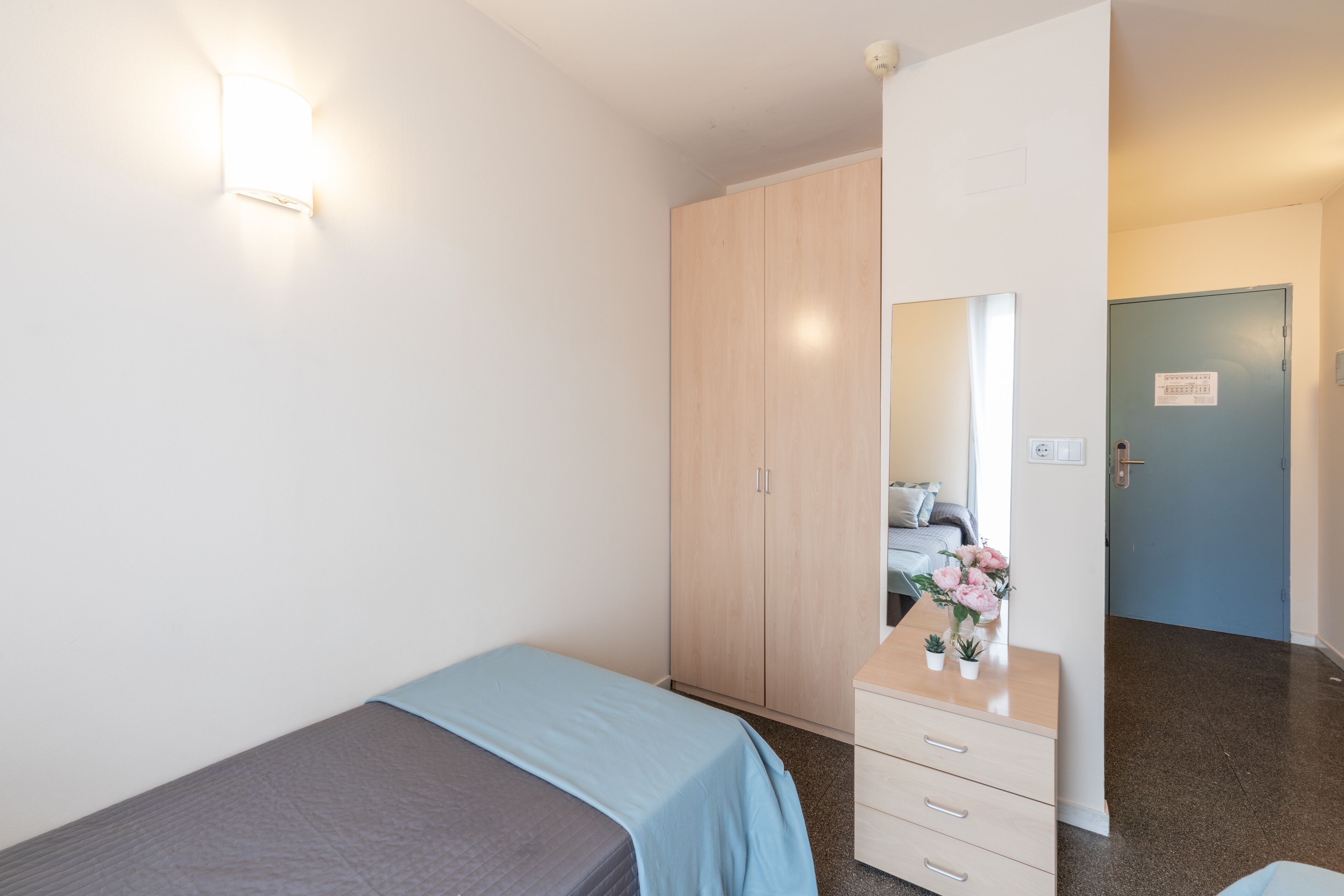 Un dormitorio con cama, cómoda, espejo y armario.