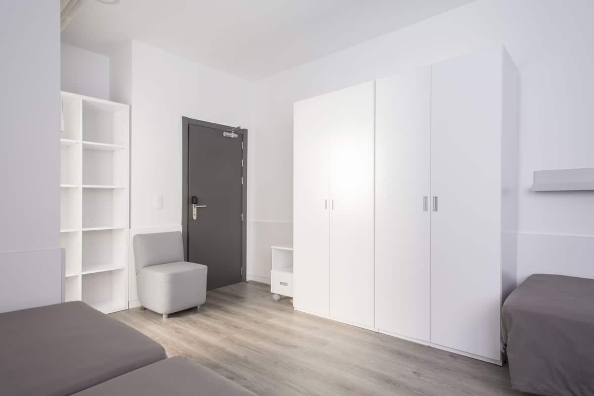 A modern bedroom with a large wardrobe, a small seating area, and a bed.