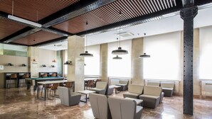 Un hall d’entrée spacieux avec une table de billard, des sièges confortables et un éclairage décoratif suspendu.