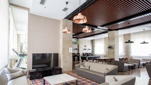 Un salon moderne avec un téléviseur à écran plat, des canapés, une table basse et un tapis coloré.
