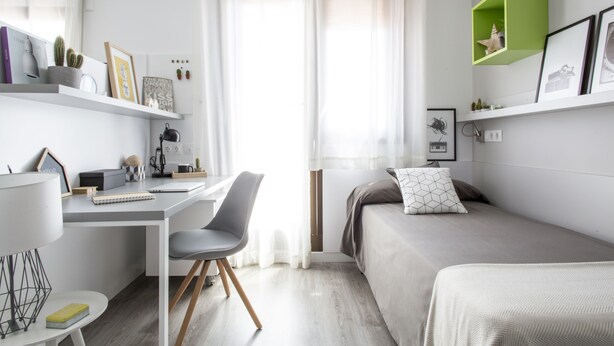 Une chambre moderne avec un bureau, un lit et une étagère verte.